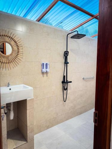 a shower in a bathroom with a sink and a mirror at The Bluhu Hill Cottage in Nusa Penida