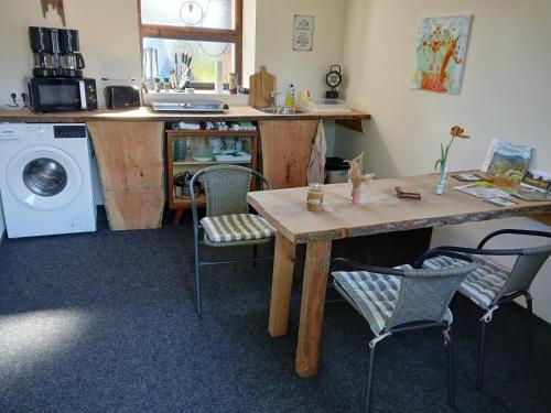 a kitchen with a table and chairs and a washing machine at Zittau - Ferienwohnung Frieda mit Camping Familien, und Biker Hütten am Zittauer Gebirge in Zittau