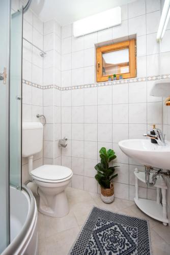 a white bathroom with a toilet and a sink at 6BDR Home in Nature in Sarajevo