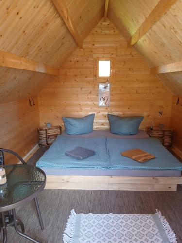 a bed in a wooden cabin with a table at Zittau - Ferienwohnung Frieda mit Camping Familien, und Biker Hütten am Zittauer Gebirge in Zittau