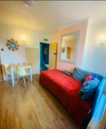 a living room with a red bed and a table at Nice bedroom close to the train station and the city centre in Norwich