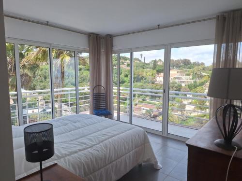 une chambre avec un lit et une grande fenêtre dans l'établissement Cannes Super Cannes Golfe-Juan - Vue mer exceptionnelle méditerranée Cap d'Antibes- Villa Alamp - 4 à 6 chambres 6 sdb 7 wc - piscine - Superbe rooftop sans vis-à-vis - grand living - Possibilité Courts séjours -, à Vallauris