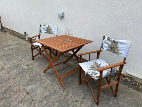 a wooden table with two chairs and a glass of wine at Bennett's End in Selsey