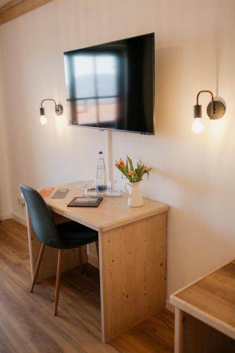 a desk with a chair and a television on a wall at ALPENHOF Westerbuchberg in Übersee