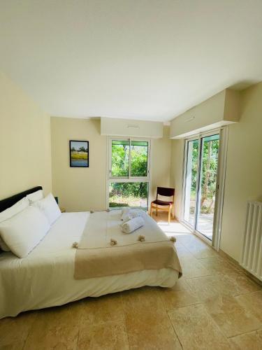 une chambre avec un grand lit et une grande fenêtre dans l'établissement Le Domaine de la Montagnette, à La Teste-de-Buch