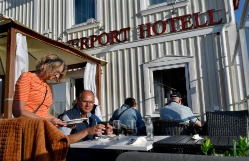 a woman sitting at a table in front of a hotel at Vänerport Lakefront Hotell in Mariestad