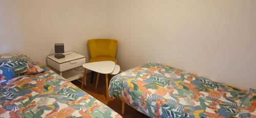 a bedroom with two beds and a chair and a table at Gîte Caves de Beauval (à 100m du zooparc !) in Saint-Aignan