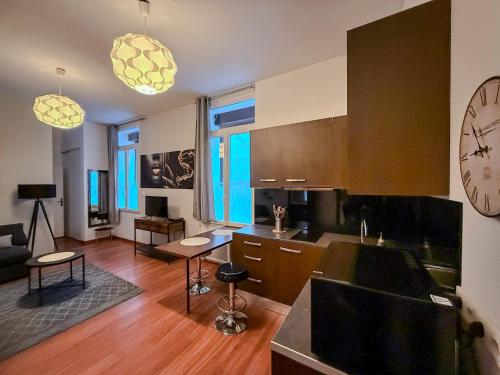 a kitchen and living room with a large clock on the wall at Studio Lumineux Proche Centre et Port in Port-Vendres