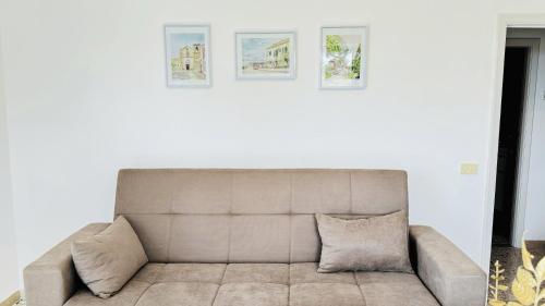Un sofá en una sala de estar con tres cuadros en la pared. en Sunshine in the City Center, en Massa Lubrense