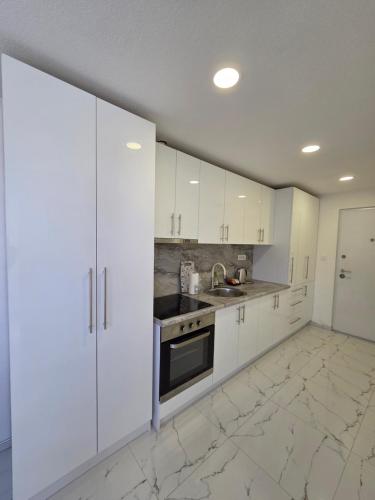 a white kitchen with white cabinets and a stove at Sarajevo Pulse Residence in Sarajevo