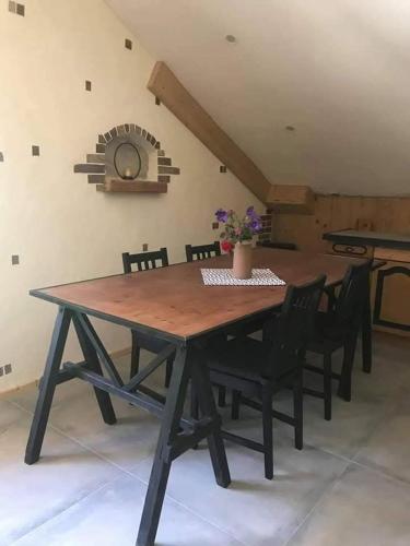 une table en bois avec des chaises et une horloge sur le mur dans l'établissement Entre lac et montagne, à Faverges