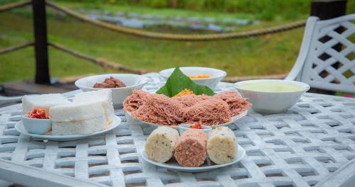 a table with plates of food and bowls on it at Green Hideaway - Villa with Private Pool, 8 mins to Galle Fort in Galle