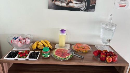 a wooden table with fruits and vegetables and a drink at Hotel Carvalho in Ibiapina