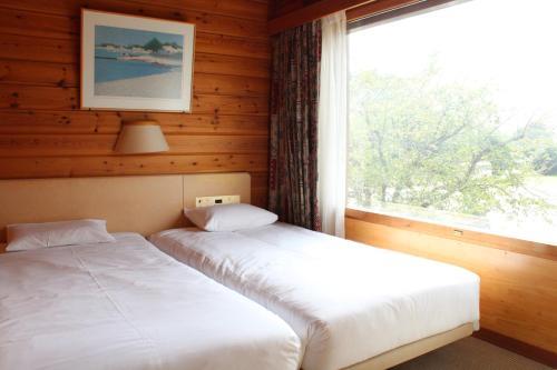 two beds in a room with a window at Grand Park Hotel Okubiwako Makino in Takashima
