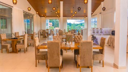 a restaurant with wooden tables and chairs and windows at Salzburg Hotels in Nuwara Eliya