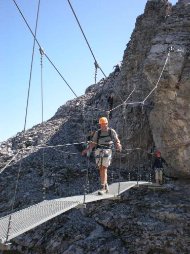 a man standing on a suspension bridge on a mountain at Hotel Restaurant Cristal in Braunwald