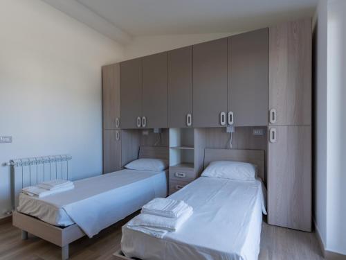 een slaapkamer met twee bedden, kasten en houten vloeren bij Rupes House in Roccella Ionica