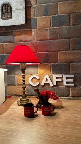 a table with a red lamp and two cups on a table at Hotel Vila Suíça 1818 in Nova Friburgo