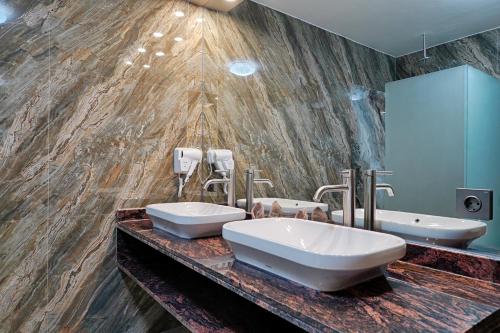 a bathroom with two sinks and a marble wall at Kyara Villa Apartments in Canggu
