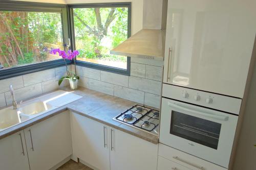 a kitchen with white cabinets and a sink and a window at Le Clos Saint Elme in Collioure