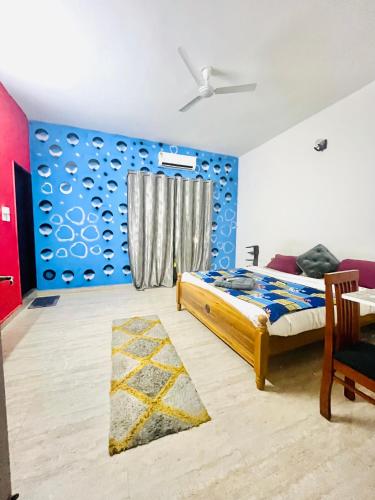 a bedroom with a bed and a blue wall at Coral Mahabs in Mahabalipuram