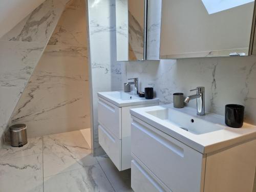 a white bathroom with two sinks and a mirror at Loft de Layolette, Laguiole centre, calme in Laguiole