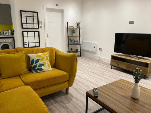 a living room with a yellow couch and a flat screen tv at Bright & Cosy Retreat in Swansea in Swansea