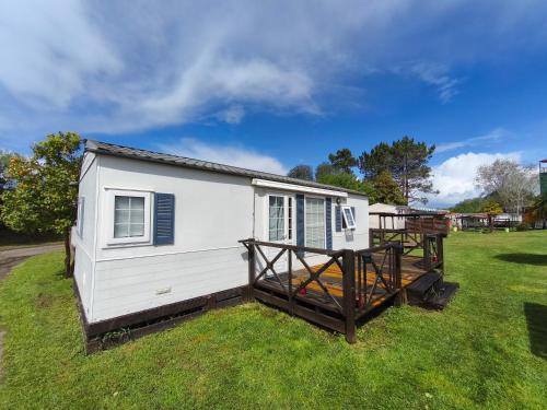 a white tiny house sitting on the grass at Casa de Camping Land's Hause in Pataias