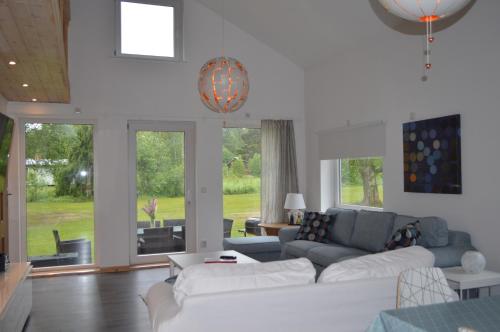 a living room with white furniture and large windows at Spacious home in a tranquil village setting in Ockelbo