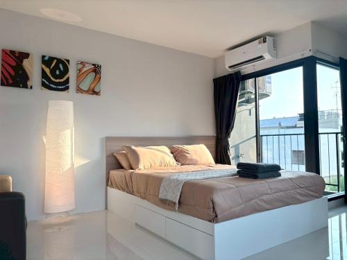 a bedroom with a bed and a large window at 4 mins to MRT Sutthisan in Bangkok