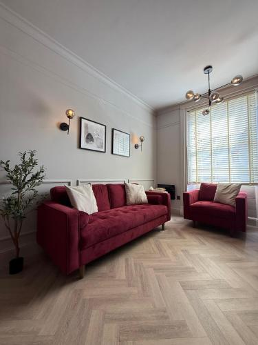 a living room with a red couch and a chair at Stunning Town Centre Apartments with Spa facilities in Morpeth