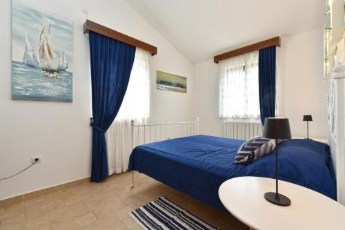 a bedroom with a blue bed and a table at Charming flat with shared pool in Peroj