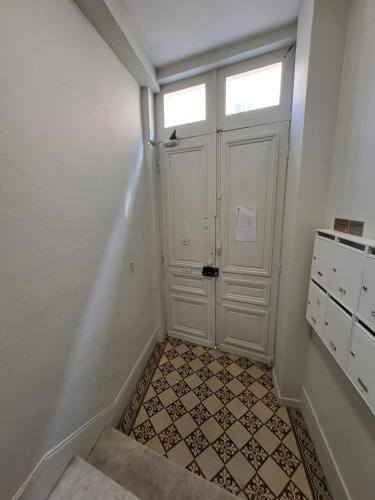 korytarz z białymi drzwiami i podłogą wyłożoną kafelkami w obiekcie Appartement de charme Rouen w Rouen