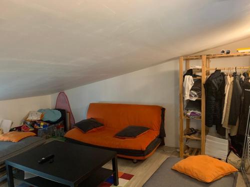 une chambre avec un canapé orange et un placard dans l'établissement Loft-style house, close to downtown and shops, à Vannes