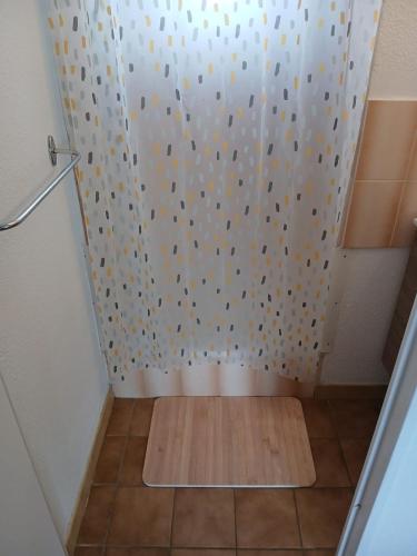 une douche avec un rideau blanc et un plancher en bois dans l'établissement Appartement 2 chambres dans la marina, à Saint Cyprien Plage