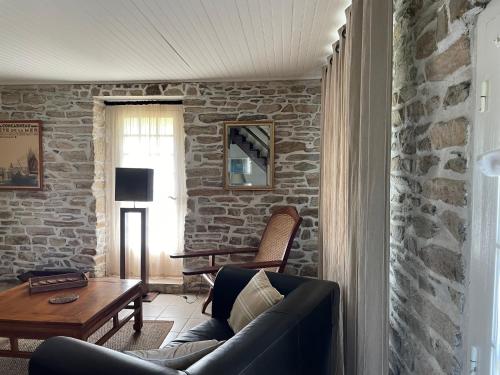 a living room with a couch and a stone wall at Adorable Penty en pierres en bord de mer in Tréogat