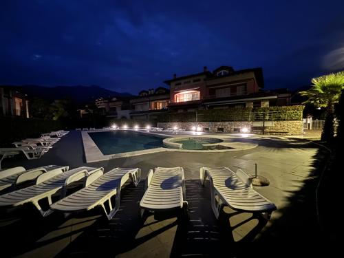a group of lounge chairs next to a swimming pool at night at Residence Lario Village in Colico