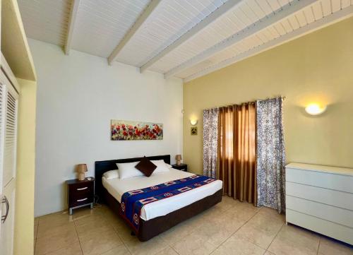 a bedroom with a large bed and a window at Bubali Gardens - Eagle Beach's Oasis in Noord