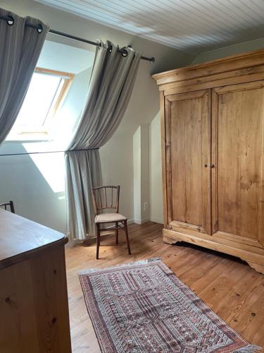 a room with a wooden cabinet and a chair and a window at Adorable Penty en pierres en bord de mer in Tréogat