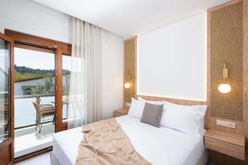 a bedroom with a white bed and a balcony at Opalium Beach Front Suites in Potos