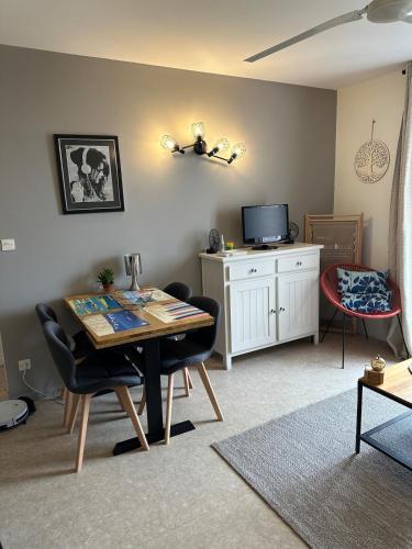 - un salon avec une table, des chaises et une télévision dans l'établissement Rochefort Appartement, à La Celle-sous-Gouzon