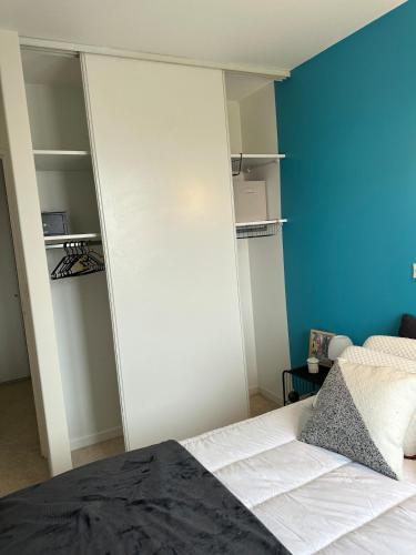 une chambre avec un lit et un mur bleu dans l'établissement Rochefort Appartement, à La Celle-sous-Gouzon