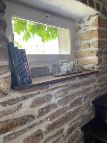 a window on a brick wall with books on a shelf at Adorable Penty en pierres en bord de mer in Tréogat