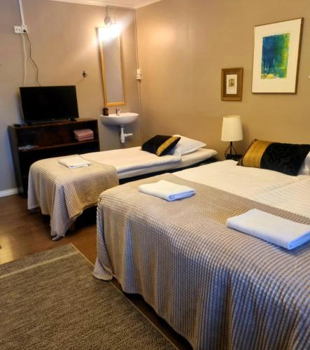a hotel room with three beds and a television at Wanha Neuvola Guesthouse in Pieksämäki