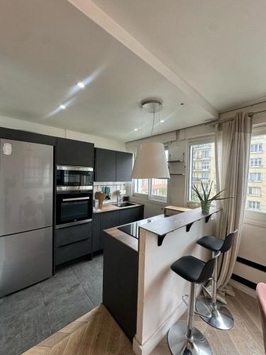 une cuisine avec des armoires en noir et blanc et un comptoir dans l'établissement Appartements Paris Expo Versailles, à Paris