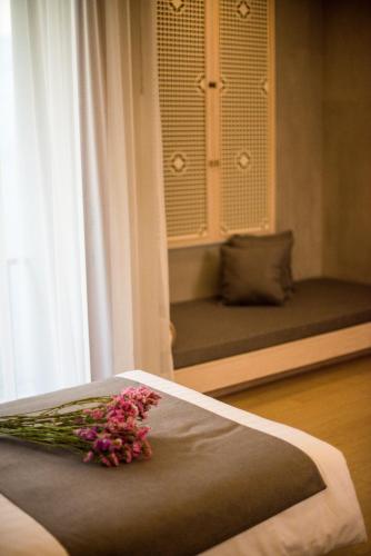 a room with a bed with a bunch of flowers on it at Chu Hotel in Chiang Mai