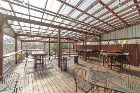 a wooden deck with tables and chairs and a pergola at RIVER OAK INN in Bandera
