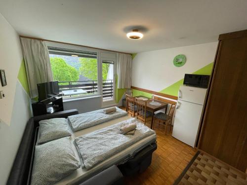 a bedroom with two beds and a refrigerator and a table at Apartma Marjeta in Bovec