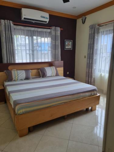 a bedroom with a bed with a wooden frame and windows at 2 bedroom house in Tema in Tema