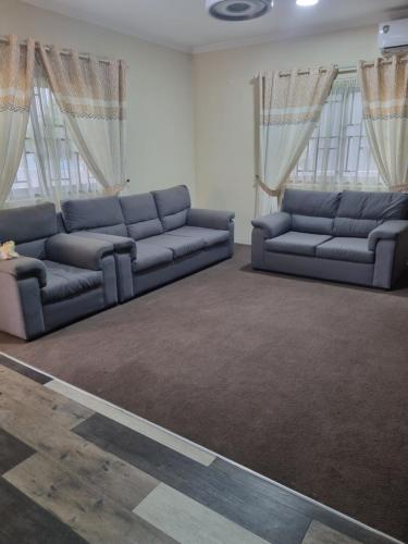 two blue couches in a living room with windows at 2 bedroom house in Tema in Tema